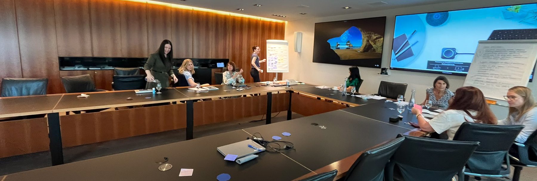 A room of people working with a LUMINUM partner, lit only where the light falls